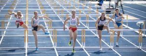 Women athletes running hurdles